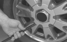 Position the chisel end of your wheel wrench, or hub cap removal tool (if equipped), in the notch of the hub cap and