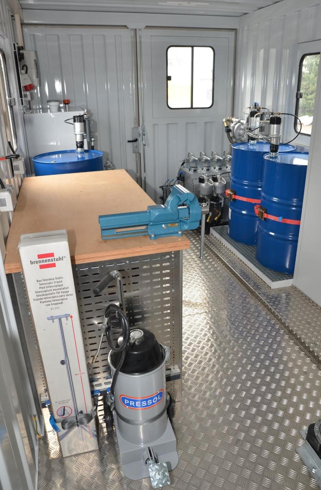 Overview of the workshop container with foot grease pump and workbench in front
