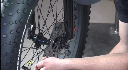 Place the wheel hub bolts in slots on front fork. Line up disc brake rotor into brake pad housing.