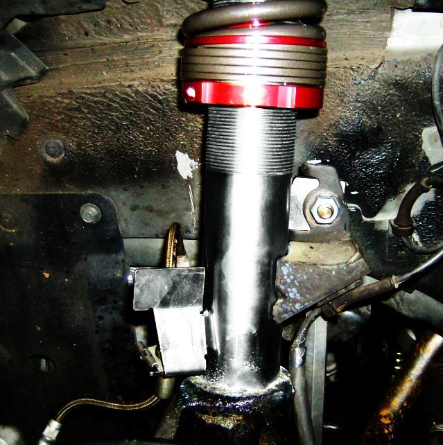 d) Line up the strut knuckle by hand, then using a jack from under the lower control arm compress the suspension to get the coilover to seat back into the knuckle (shown in Figure 5d).
