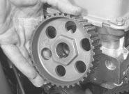 Keep it taut, and engage it with the teeth of the camshaft sprocket.