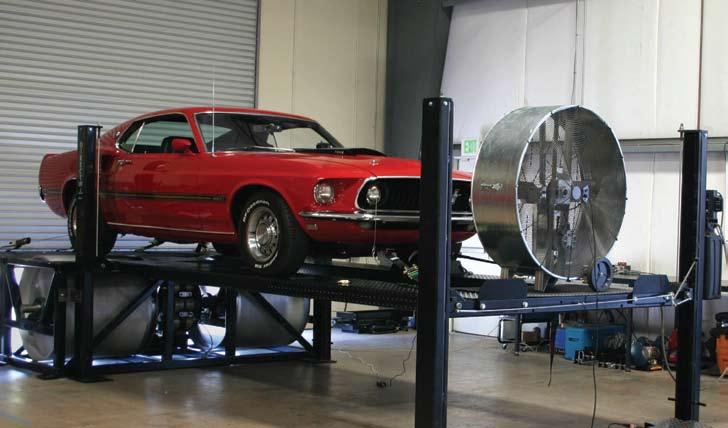 CHASSIS DYNAMOMETER TESTING This muscle Mustang is on a large roll dyno about to be tested. The Mustang is on a lift so the dyno can be mounted above floor line.