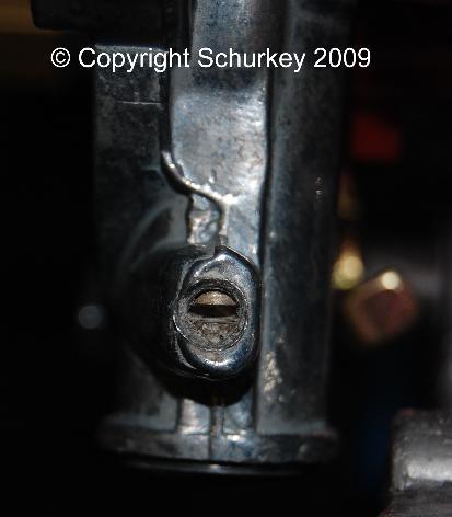 Holley seals the pulloff piston adjusting screw under the caulking. Caulking removed; and the adjuster screw turned way too far in, as seen with the end seal pried off of the choke housing.