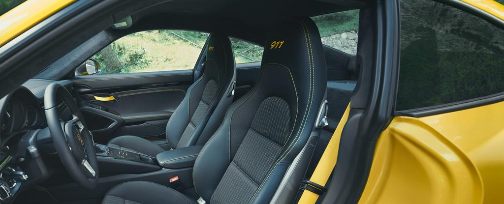 The new 911 Carrera T accelerates from 0 to 100 km/h in 4.5 seconds. And pushes you back forcefully into the Sports seats Plus, fitted as standard. Embroidered on the headrests: the 911 logo in black.