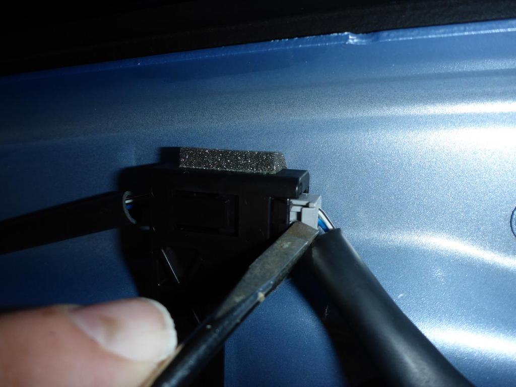 Close up of above photo, Center 1/3 of hatchback Just use a screwdriver to press on that little tab, then slide the wire jack out of its receptacle PRESS IN THIS TAB Slide wire jack out of receptacle