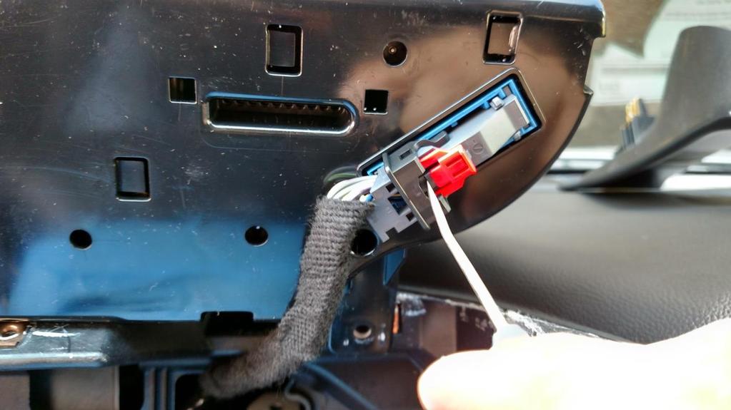 There is a red safety lock, with your thumb slide the red safety tab away from the harness.