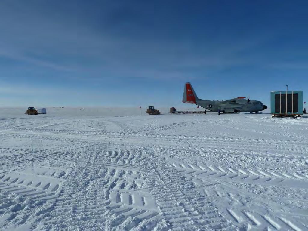 An LC-130 is being unloaded while a pallet of ice cores waits to be loaded at the left.