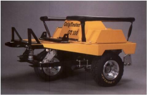 It can be towed behind a vehicle with an automatic water delivery system or pushed by hand by the operator. The GripTester has one test wheel that is braked and two bogey driving wheels (figure A.1b).