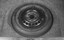 Turn the center nut on the compact spare tire cover counterclockwise to remove it.