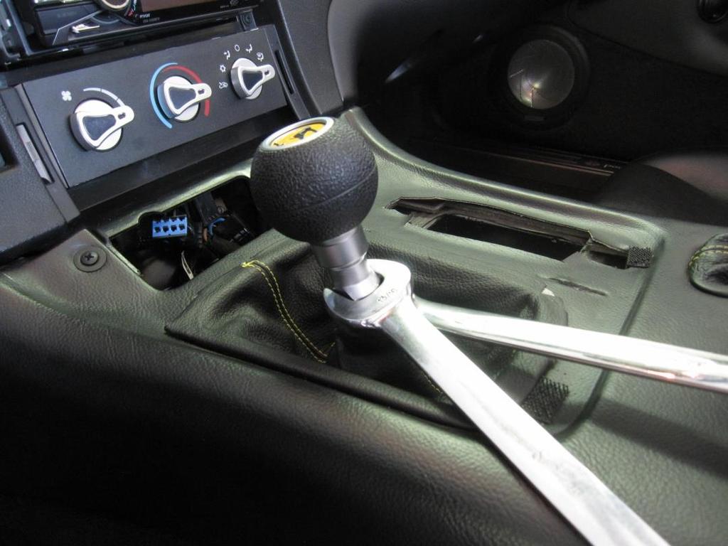 2 Remove the center console Place the original shifter in 3rd gear Remove the shift knob Push the upper shift boot down until the retaining nut is accessible Place the 3/4" wrench on the retaining