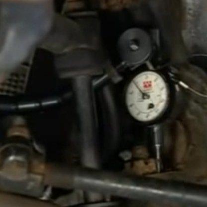 Fasten a dial indicator to the control arm, then clean off the flat on the spindle next to the ball joint stud nut.