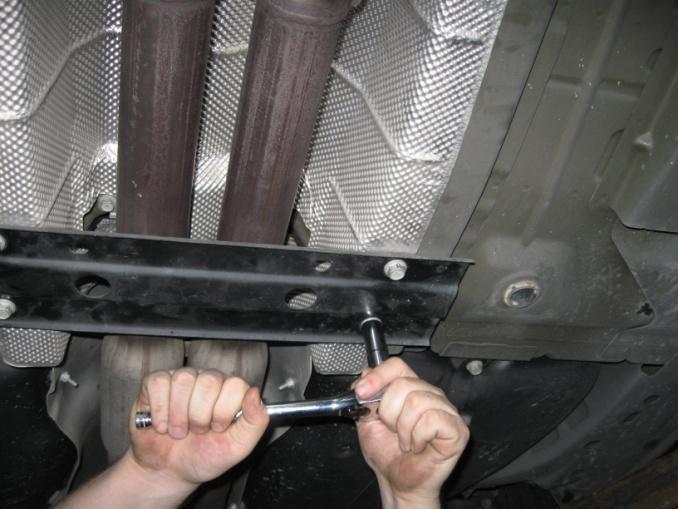 3 5. Underneath the car, remove the black plate towards the back of the car by taking off (4) screws