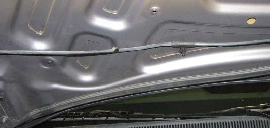 Use a panel puller to pry off two of the push-pins holding the hood insulator in place on the passenger side, then reach behind the insulator to disconnect the washer hose from the T-junction at the
