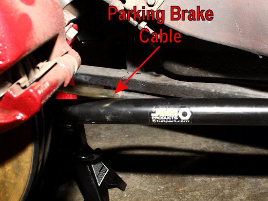 The parking brake cable will simply rest on the suspension arm, once you