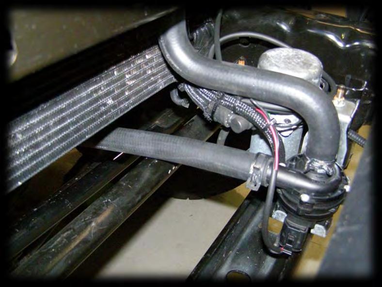 Route the hose through the gap on the upper LHS of the radiator shroud and pass the hose down beside the
