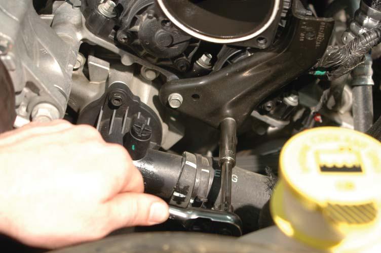 Use a 10mm socket to remove the two bolts holding the mounting bracket to the front of the engine on the