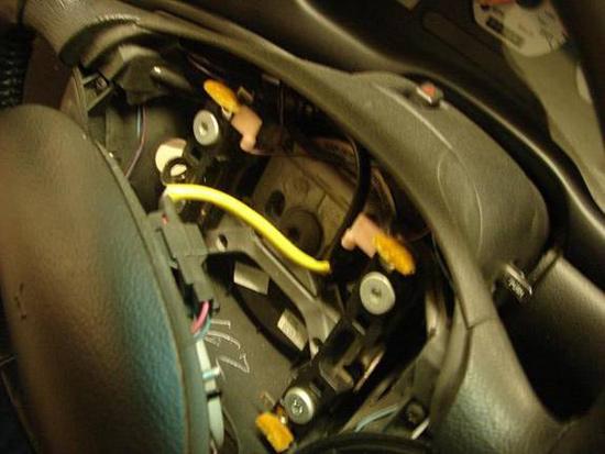 4. Now the 5/16 retaining screws for the airbag can be seen. Remove the screws. 5. Gently lift the airbag straight off the wheel and disconnect the yellow wire from the module on the airbag.