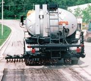 Spray a metered and controlled amount of liquid asphalt in front of a self propelled chip spreader in a chip seal road