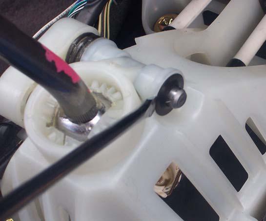 Insert a small sharp flat head screw driver behind the clip on the right front side of the assembly and pry the