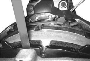Turn the adjuster counterclockwise with an 8 mm deep offset box end wrench until both brake pads contact the brake rotor. C. Remove the feeler gauge.