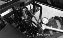 On the 700 to adjust air pressure on the rear shock absorbers, connect the air pump to the valve fitting on the top of the shock absorber and pump (to increase pressure) or depress bleed valve (to