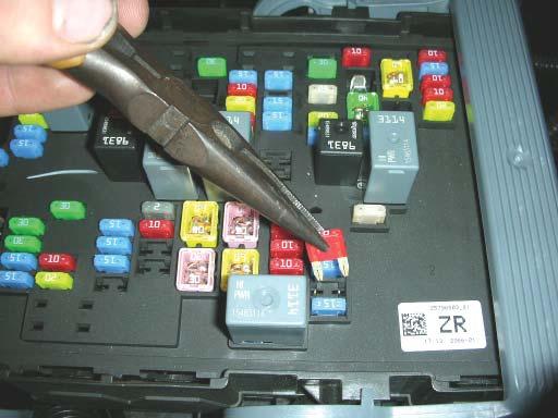113. Pull back on the two tabs holding the fuse cover to the fuse box and lift the cover out of the