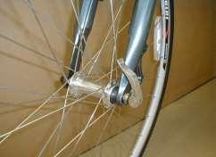 Insert the wheel between the fork blades so that the axle seats firmly at the top of the fork dropouts (1-A & 1-B), which are at the tips of the fork blades.