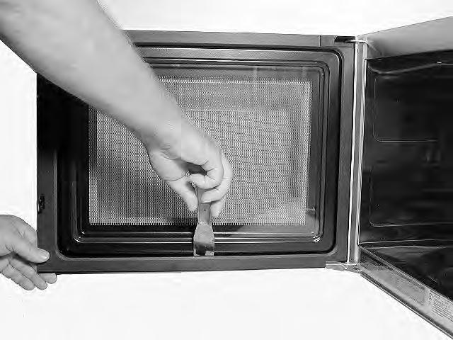 c) Pull out on the cover to release all of the locking tabs, and remove the cover from the door. CAUTION: When you work on the microwave oven, be careful when handling the sheet metal parts.