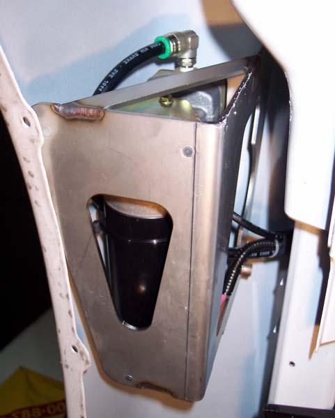 Locate the hood support bolt up inside of the fender well; it is very close to the bottom of the radio antenna. Remove the bolt closest to the battery tray or closest to the front of the vehicle.