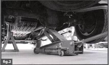 Using a floor jack (FIG 2) rated to handle the vehicle weight, align under the rear end housing and raise the rear of the