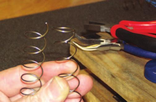 I use a pair of non-marring (without grooves) pliers to bend the spring to have a fl at coil at each end.