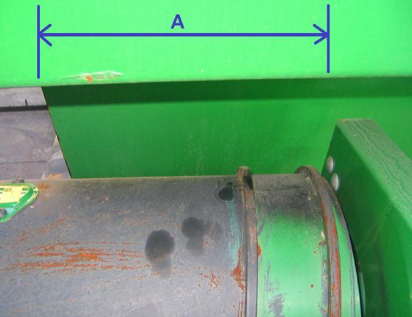 Slide the draper transfer belt frames towards the center until they overlap the feeding auger by 23 cm (9 in).