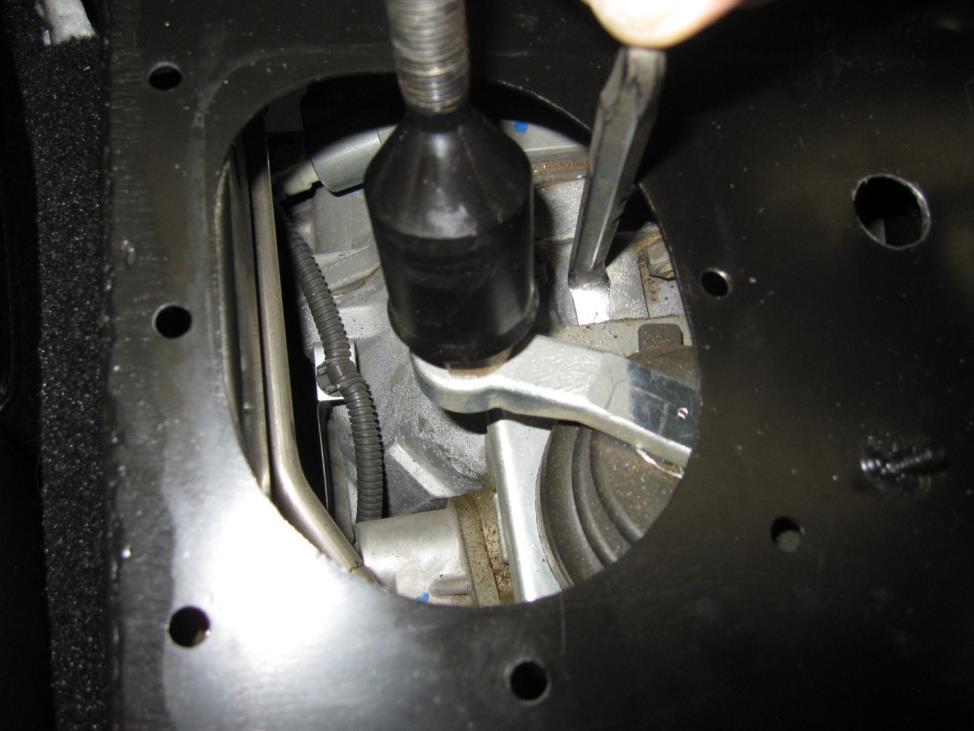 Push aside the connector that is kept down by the forward passenger side cover mounting bolt Use the small pry bar to break the original shifter away from the transmission tail
