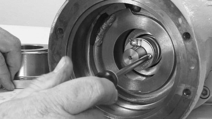 Compress the seal assembly spring with both thumbs to expose the locking pin hole on the shaft. Install the locking pin into the hole on the pump shaft.