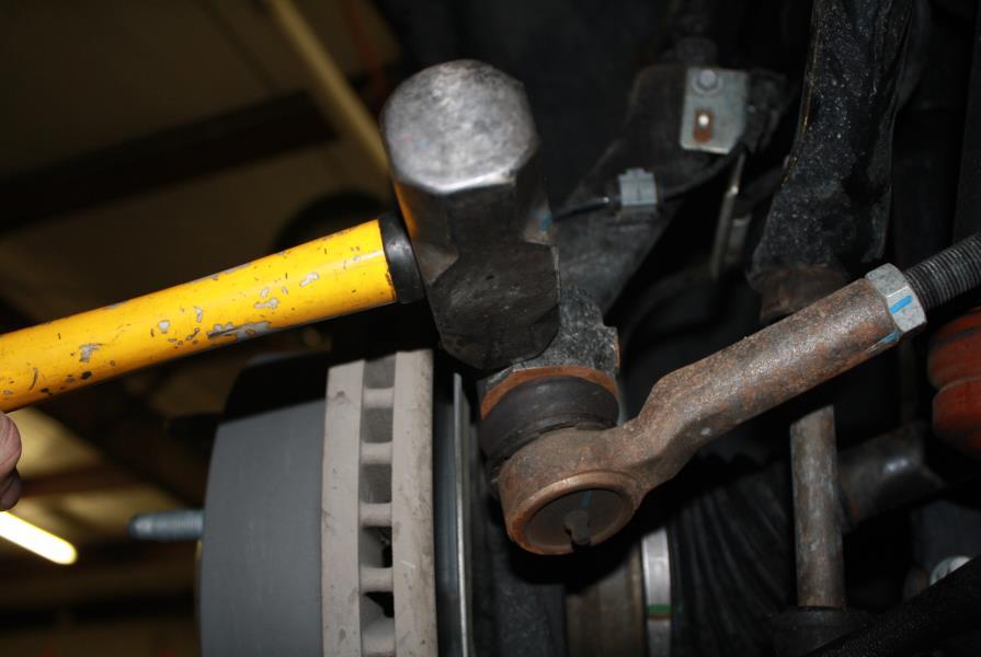 To do this, remove the nut holding the outer tie rod end to the spindle, then while prying the tie rod away from the spindle, hit the spindle with a hammer in the position as shown in figure 9.
