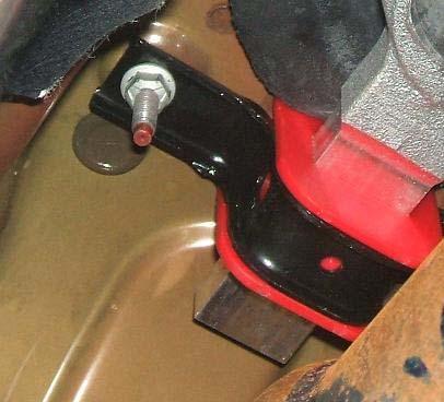 22. Using the take off saddle bracket, attach the rear isolator of the shifter assembly to the floor pan studs. Slide the red isolator on the arm as required.