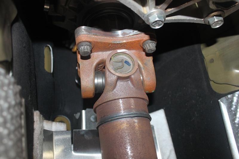 8. The middle of the drive shaft is held on by a factory safety loop with two bolts. Use a 13mm socket with an extension to remove the two bolts. 9.
