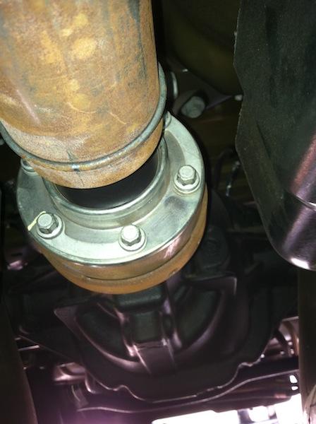 12. Go to front of car and remove final bolt on the transmission flange. Use pry bar to remove the driveshaft off the flange.