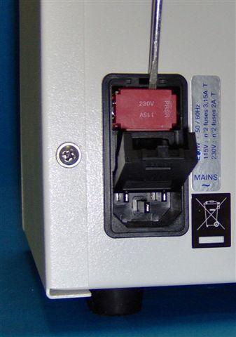 The voltage setting is written in white, on a red background, on the top of power setting and fuse holder. The factory setting is 230V. Fig. 5a. Fig. 5b.