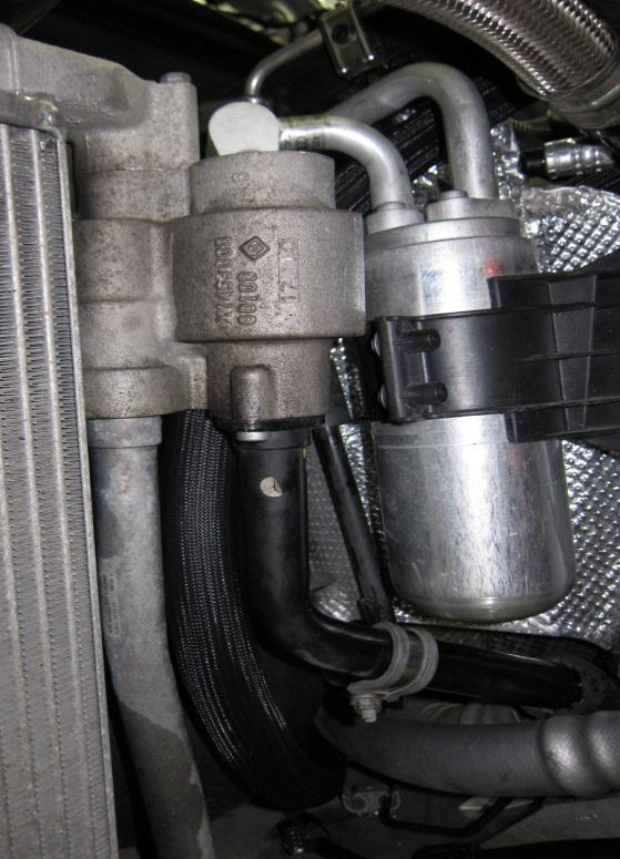 The hose routes up along the inside of the oil cooler and around the heat shield to the engine compartment.