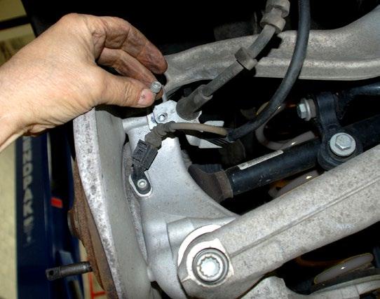 To access the front subframe bolt, remove the plastic underbody panel just ahead of the rear wheel, held in place by several screws.