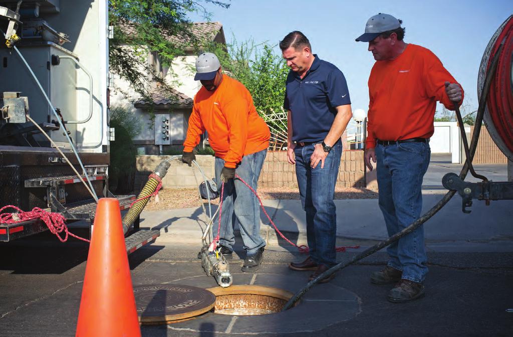 Yusuf Munir (left) lowers a camera into a manhole to begin an inspection with Chris Mihaletos (center) and Tom Verbridge.