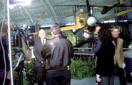 Photo by Paul Kennedy Warhawk. Opening day finds Don Lopez, deputy director of NASM, talking to the press as a P-40 Warhawk bearing his name flies through the gallery.