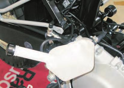 - Loosen the two upper retaining screws (1) of the expansion tank (2) on the left side of the motorcycle.