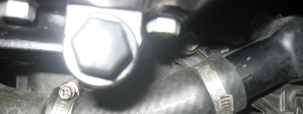 Figure 6: Other end of metal coolant transfer line has a rubber hose section that connects it to the coolant pump inlet. The coolant pump is just visible on the right.