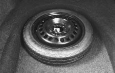 Turn the retainer (center dial) on the compact spare tire cover counterclockwise to remove it.