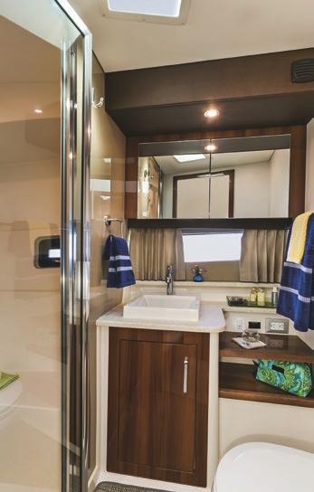 solid-surface countertop and vessel sink, a wood-framed mirror, an opening portlight and plenty of storage.