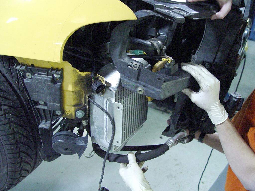 Wiggle the intercooler in between the AC lines and the radiator support. It is a tight area, so have some patience.
