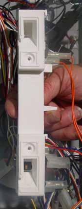 Using a small screwdriver, release the tab and remove the door interlock switch from the door switch bracket. Disconnect the electrical connector.