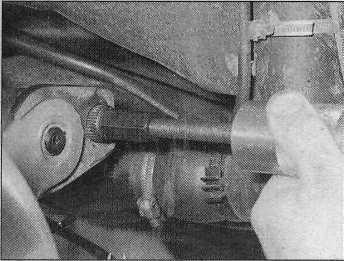 14a Attach the position bracket (1) to the shock absorber lower mounting bolt hole as shown, using the mounting bolt and nut and a suitable spacer A tool to hold the trailing arm in position can be